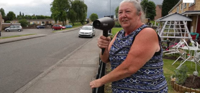 A 64 éves hölgy az autóvezetők felé tartja a hajszárítót… a szomszédok hősként ünneplik, mióta rájöttek miért teszi