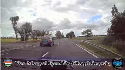 Kép a videóból, ahogyan a rendőrautó mellett elsuhan az okostojás, a Suzukijával.. Hirmagazin.eu