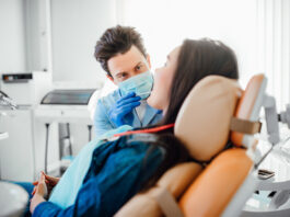 portrait dentist blue mask working with patient modern clinic