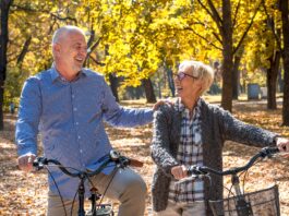happy elderly couple riding a bicycle in the park in the autumn