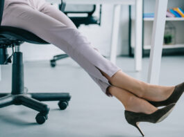 cropped shot of businesswoman in stylish high heeled shoes sitting at workplace