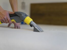 employee of cleaning company cleans and disinfecting the mattress using a washing vacuum cleaner. furniture dry cleaning process