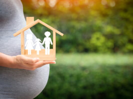 women,is,pregnant,hand,hold,a,wooden,home,with,happy